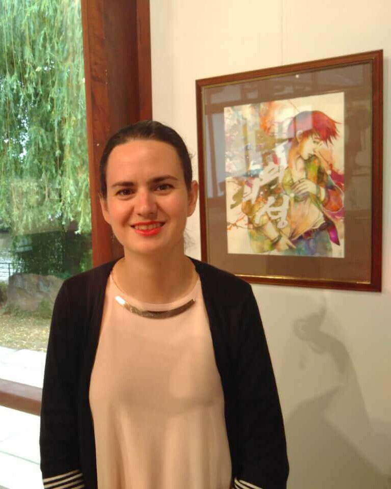Claire Pacheco, artiste peintre et professeure à l'Atelier Adya, posant devant une de ses œuvres lors de son exposition à l'Île de Versailles à Nantes